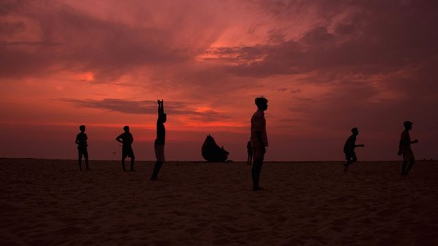 Boys waiting for a corner kick during a game of football on Arthunkal Beach, Kerala, India.