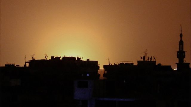 На фото, сделанном из удерживаемого постанцами города Дума, видны всполохи огня в районе аэропорта Дамаска