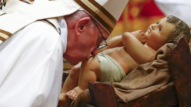 Pope Francis kisses a statue of baby Jesus at the end of the Christmas night Mass in Saint Peter's Basilica at the Vatican December 24, 2016