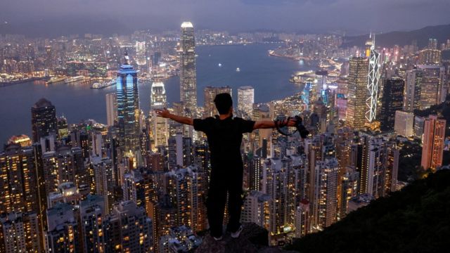 香港太平山上一位游客边俯瞰夜景边张开双臂（9/5/2023）