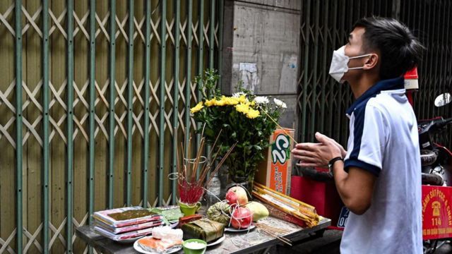 Man lighting incense at apartment block