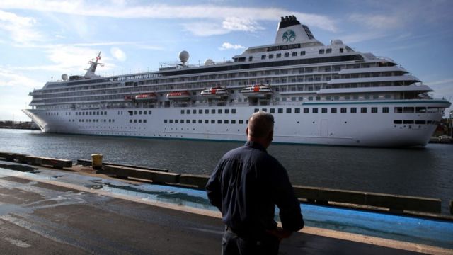 Un hombre mira un crucero que llega al puerto