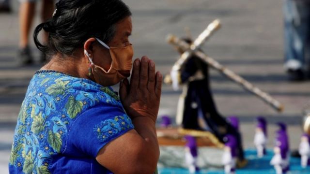 Guatemalteca rezando con mascarilla.