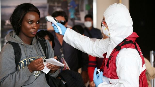 Personal de salud de Ecuador toma la temperatura de pasajeros en el aeropuerto.