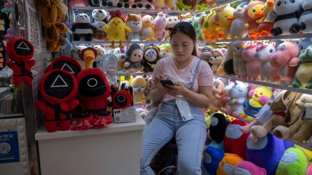 مندوبة مبيعات تجلس في متجر يبيع ألعاب مستوحاة من "سكويد غايم" في أكبر سوق للسلع الصغيرة في العالم، في في ييوو، مقاطعة تشغيانغ، الصين