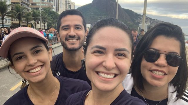 Lísia e mais três amigos na orla do Rio de Janeiro, sorrindo para selfie