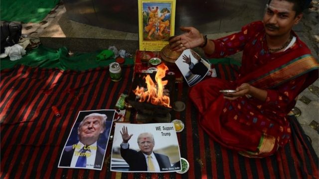 An Indian Hindu priest performs a Hawan (The Sarced Fire) ritual alongside posters bearing the image of US Republican presidential candidate Donald Trump in New Delhi on May 11, 2016.