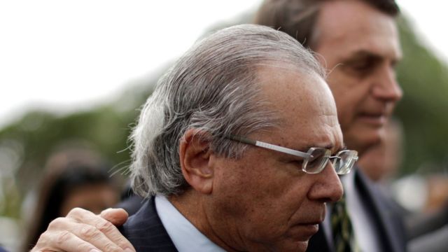 Paulo Guedes e Jair Bolsonaro aparecem abraçados e de perfil