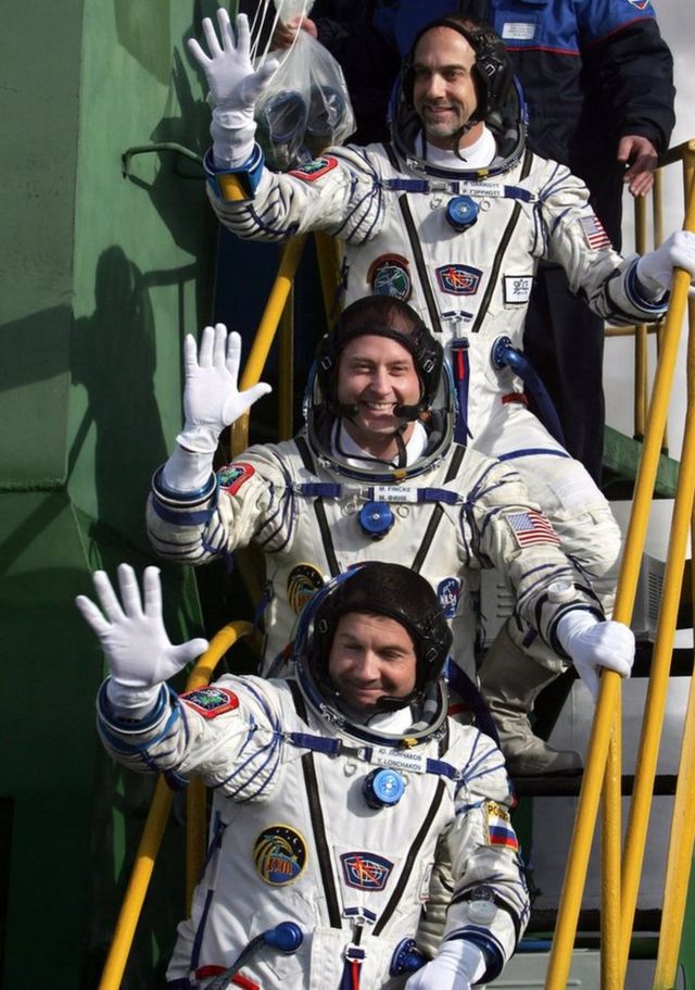 Le cosmonaute russe Yury Lonchakov (en bas), l'astronaute américain Michael Fincke (au centre) et son compatriote, le touriste de l'espace Richard Garriott (en haut), saluent en montant à bord du vaisseau spatial au cosmodrome de Baikonur, au Kazakhstan, le 12 octobre 2008.