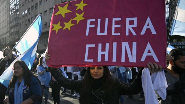 Una mujer sostiene un cartel que dice "Fuera China"
