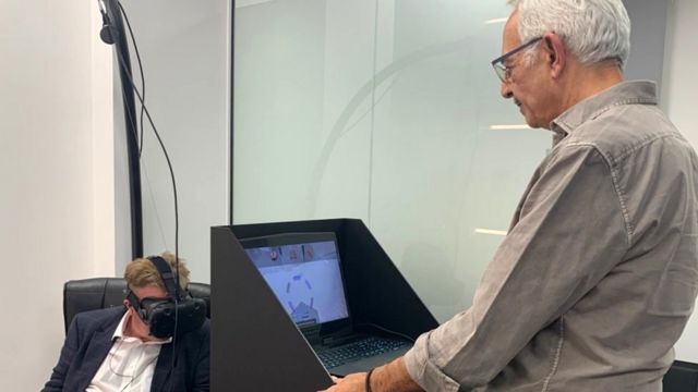 ไมเคิล เดมป์ซีย์ กำลังสวมอุปกรณ์ ส่วน ดร.จามิล เอล-อิหมัด ยืนอยู่หน้าจอคอมพิวเตอร์
