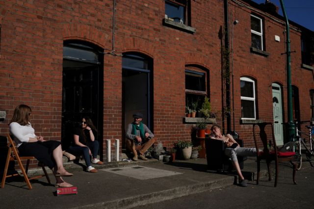 People chat while social distancing outside their homes