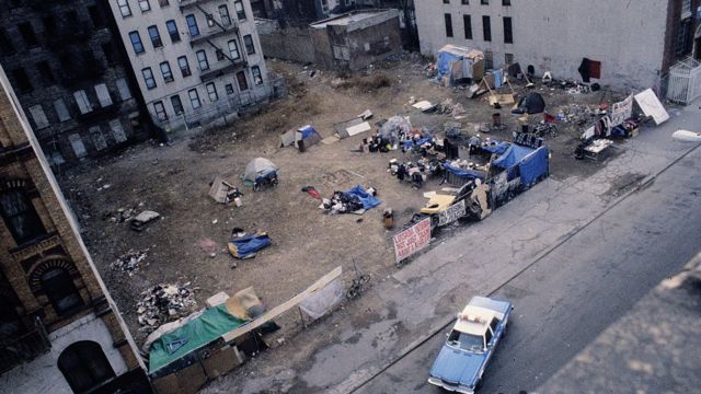 Viatura da polícia observa acampamento de sem-tetos montado em um terreno abandonado no East Village, Nova York, em 1991