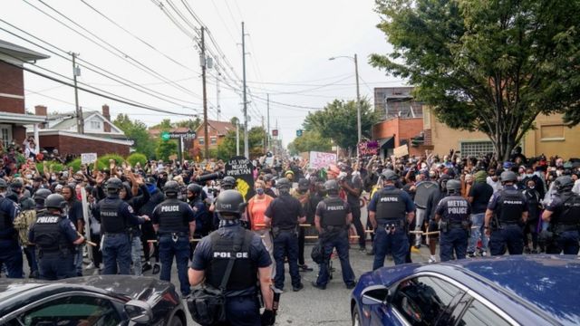 Police stand guard as people react after a decision in the criminal case against police officers involved in the death of Breonna Taylor