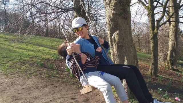 Yau's wife and son smile while on a swing