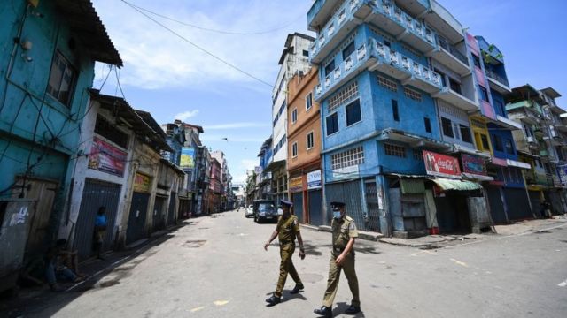 ஏப்ரல் 28, 2022 அன்று கொழும்பில் மூடப்பட்டிருக்கும் ஐந்தாவது குறுக்குத் தெரு மொத்த விற்பனைச் சந்தையில் ஒரு தெருவில் போலீஸ்காரர் நடந்து செல்கிறார்