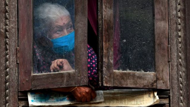 Mujer enmascarada mirando por la ventana
