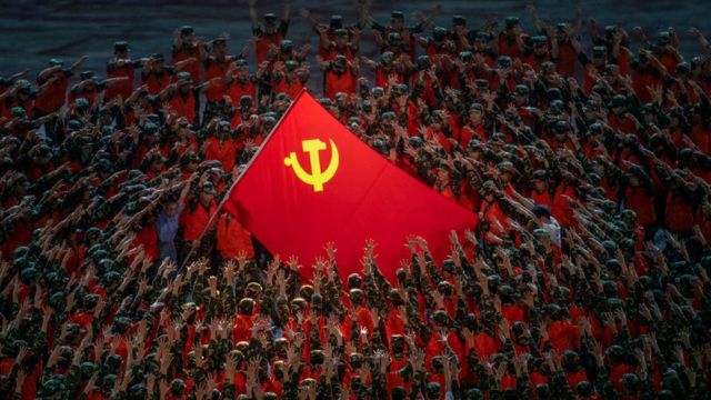 Performers in the costume of emergency workers surround a large Communist Party flag during a mass gala marking the 100th anniversary of the Communist Party on June 28, 2021.