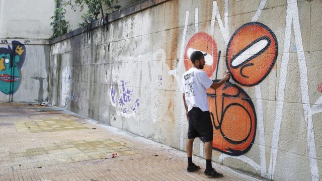 Homem grafita parede no Centro de São Paulo