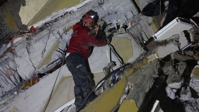 Uma equipe de resgate procura vítimas e sobreviventes em meio aos escombros de prédios desabados em Kahramanmaras, Turquia