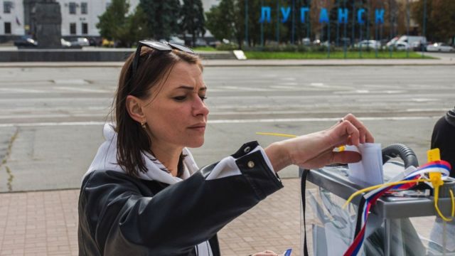 A woman votes at an outdoor polling station on the streets of Luhansk