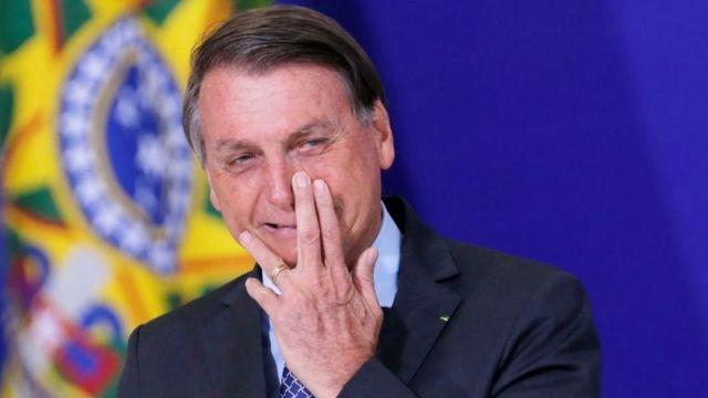 Em evento, Bolsonaro sorri com a mão no nariz