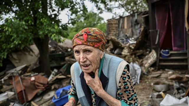 امرأة خارج منزلها المتضرر بعد سقوط صاروخ عليه في باخموت، دونباس في 22 مايو / أيار
