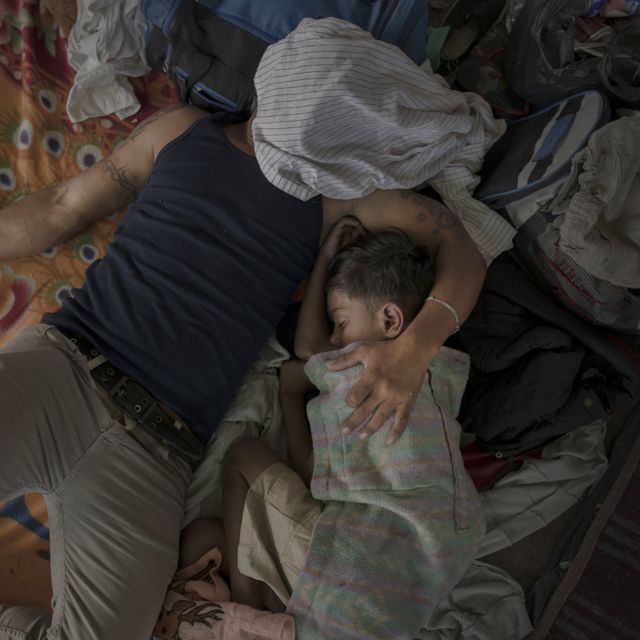 A father and child sleep on a bed