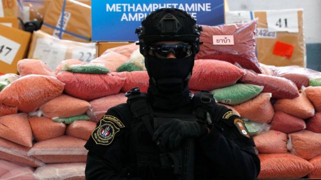 Тайский полицейский караулит пакеты с экстези и другими стимуляторами амфетаминового ряда