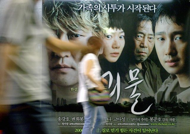 Una mujer pasa frente a una valla publicitaria de la película "The Host" en Seúl