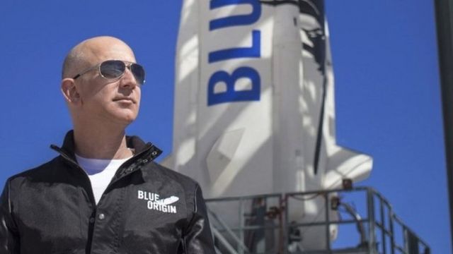 Bezos ao lado de foguete com nome 'Blue Origin'