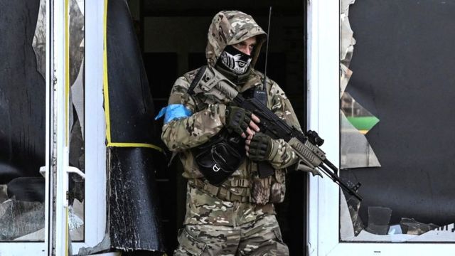 A Ukrainian serviceman exits a damaged building after shelling in Kyiv, 12 March 2022