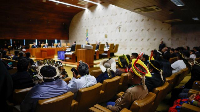 Plateia acompanhando votação no plenário do STF, alguns dos quais com trajes típicos indígenas