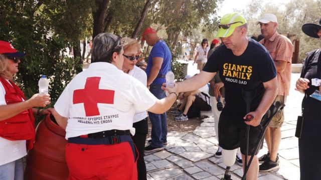 Voluntários da Cruz Vermelha Helênica distribuindo garrafas de água em Atenas na sexta-feira