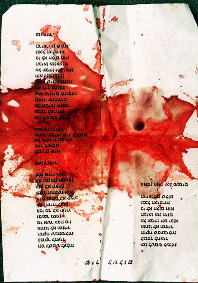 Una papel con la letra de la "Cancion por la paz" manchado de sangre.