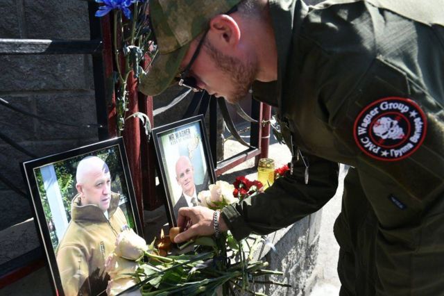 Un adepto del grupo Wagner enciende una vela frente a la foto de Yevgeny Prigozhin en San Petersburgo