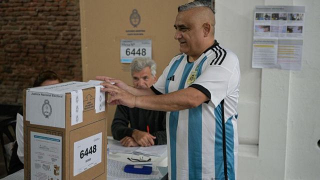 Un hombre vota con la camiseta de Argentina.