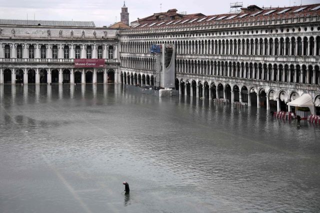 A man crosses the flooded St. Mark's Square in high water levels in Venice, 13 November 2019