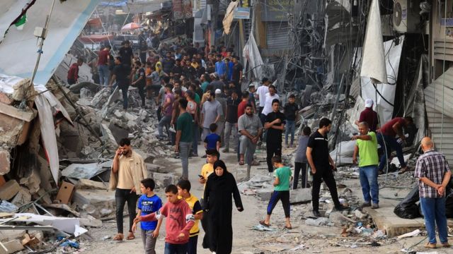 Palestinians walk amid the rubble of destroyed and damaged building in the heavily bombarded city centre of Khan Yunis in the southern Gaza Strip following overnight Israeli shelling, on 10 October 2023
