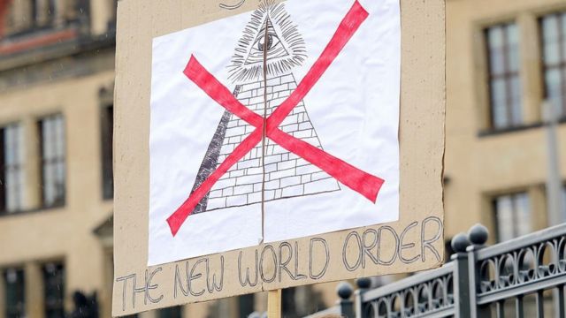 Uma placa de manifestante diz "Pare a nova ordem mundial"