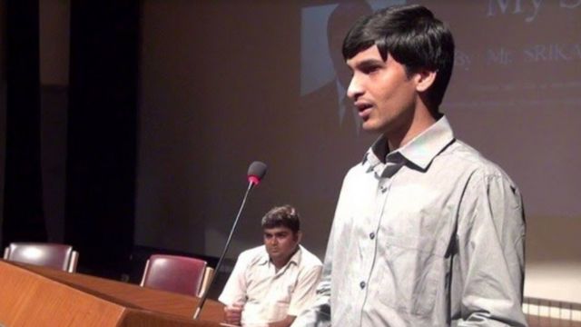 Srikanth Bolla standing at a lectern mid-speech