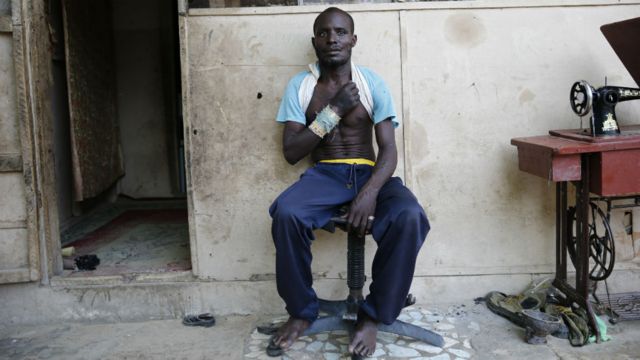 A volunteer vigilante sits outside his house after a fight against Boko Haram