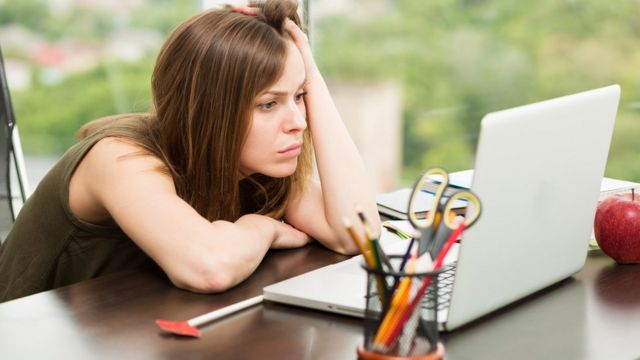 Mujer frente a una computadora con el rostro preocupado.