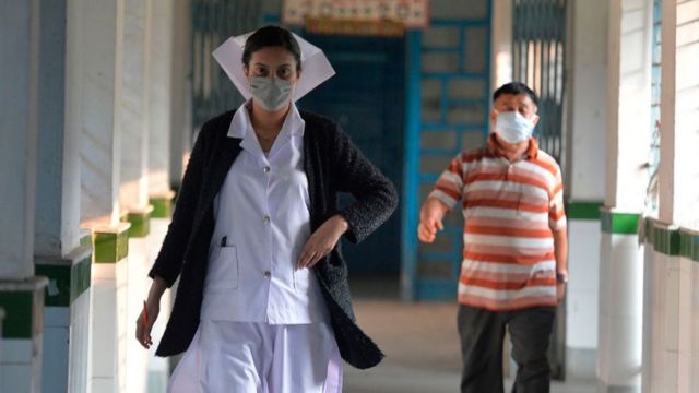 A medical member of staff wearing a facemask walks along a corridor in Bengal