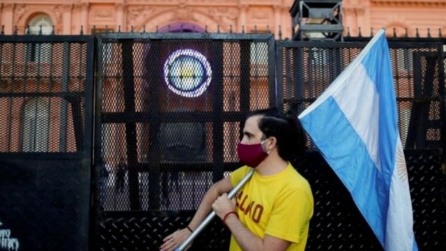 Homem segura a bandeira da Argentina durante protesto em frente à Casa Rosada, em Buenos Aires
