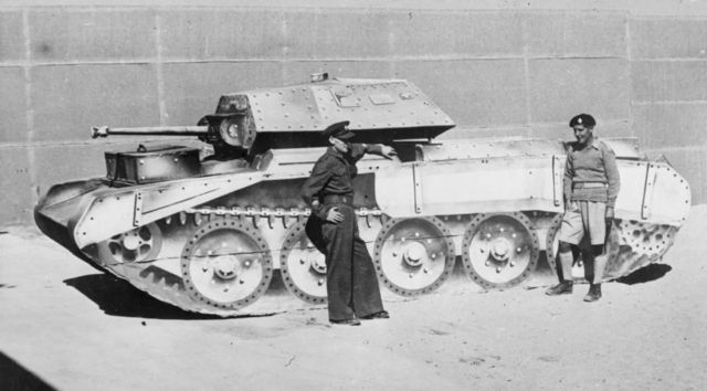 Foto preto e branco mostra homens ao lado de um tanque de guerra falso