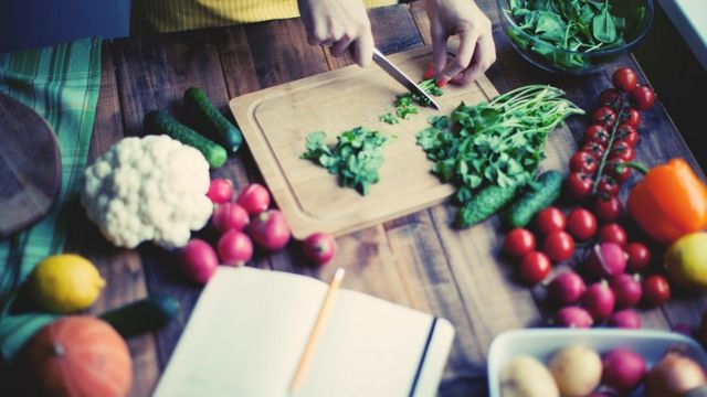 Mulher cortando produtos de origem vegetal