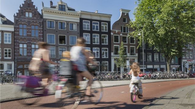 Adultos y niños andando en bicicleta por Ámsterdam.
