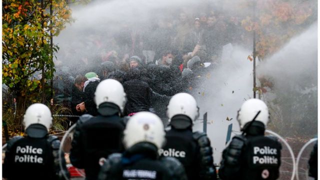 Protesters face riot place clash during an anti-coronavirus measures protest in Brussels Belgium, 21 November 2021. In a move to tackle yet another COVID-19 wave, the Belgian government imposed strict measures, pushing thousands to the streets to protest against mandatory vaccinations, health pass and anti-coronavirus measures. EPA/STEPHANIE LECOCQ