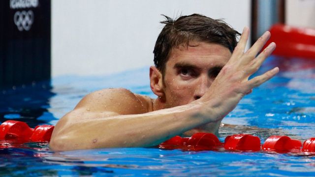 Michael Phelps faz o número quatro com os dedos, indicando ser o único tetracampeão na mesma prova olímpica